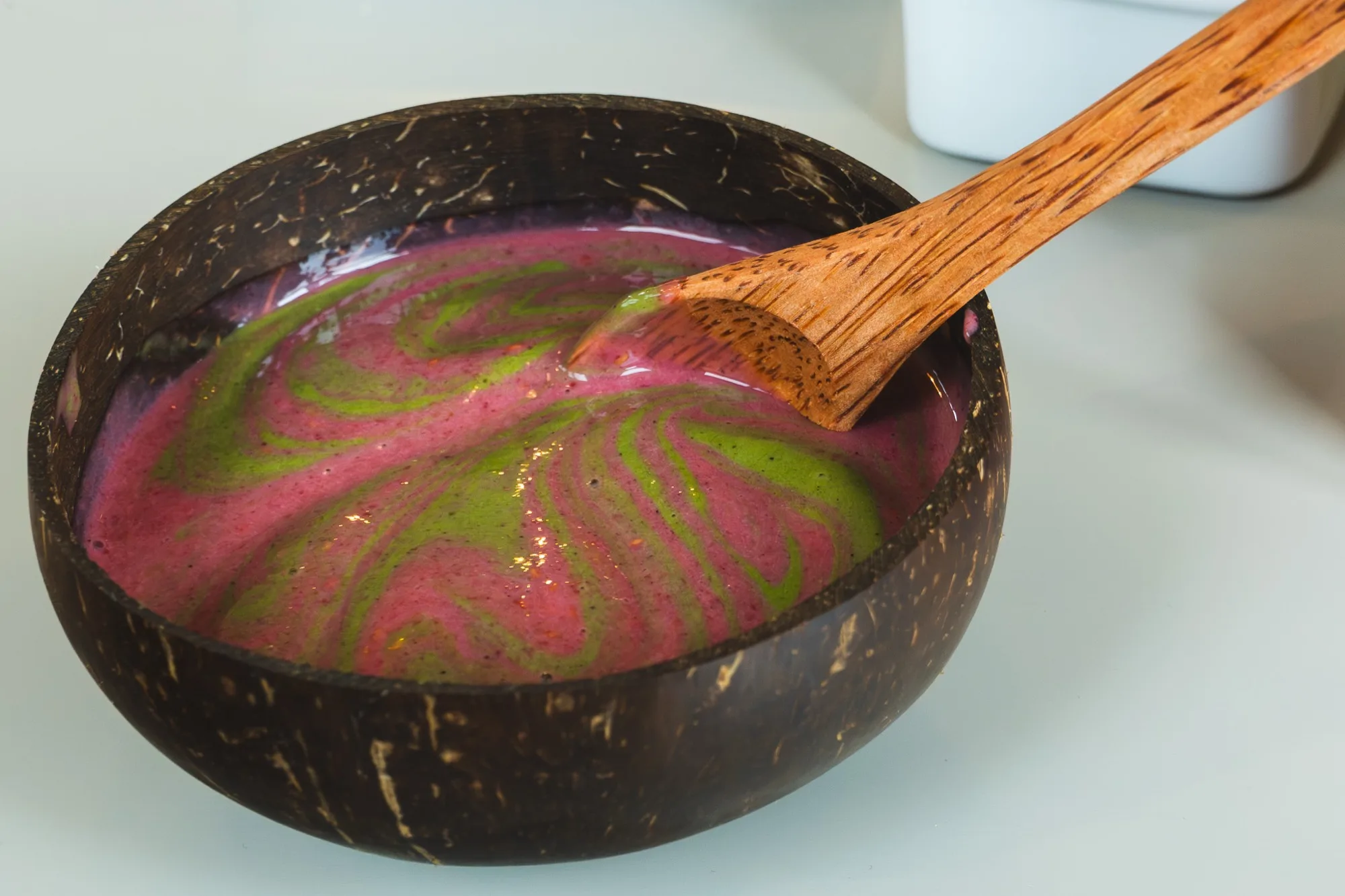 Green smoothie with swirl in coconut bowl